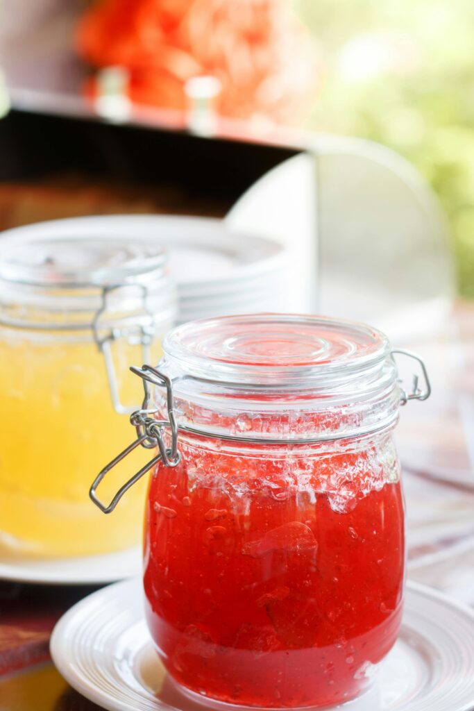 Close-up of homemade red and yellow jams in glass jars, conveying a fresh and delightful culinary experience.
